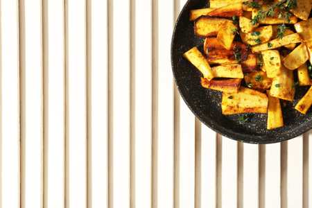 Delicious parsnips with thyme in frying pan on white wooden table, top view. Space for text