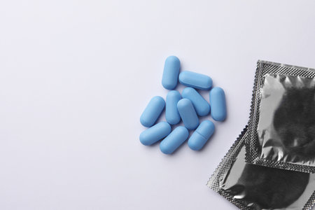 Pills and condoms on white background, flat lay with space for text. Potency problemの写真素材