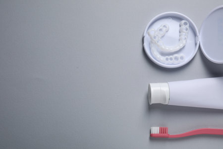 bit correction. Toothpaste, brush and dental mouth guards on gray background, flat lay. Space for textの写真素材