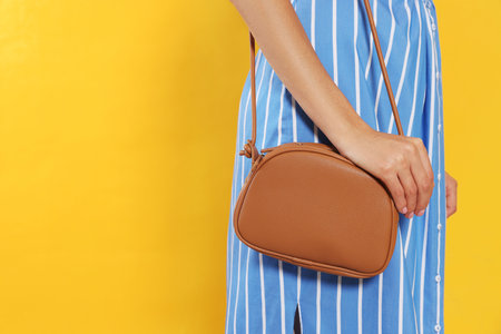 Woman with stylish bag on orange background, closeup. Space for textの写真素材