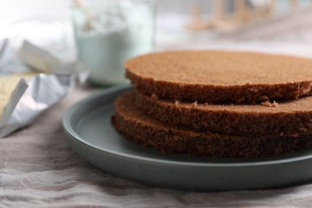 Delicious homemade sponge cakes and ingredients on gray tablecloth, closeup