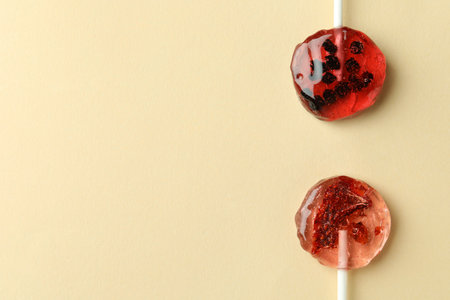 Sweet colorful lollipops with berries on beige background, flat lay. Space for textの写真素材