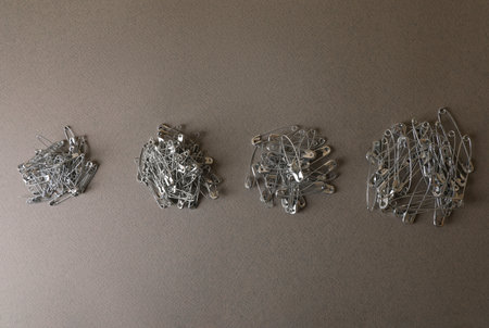 Piles of safety pins on gray textured background, flat lay