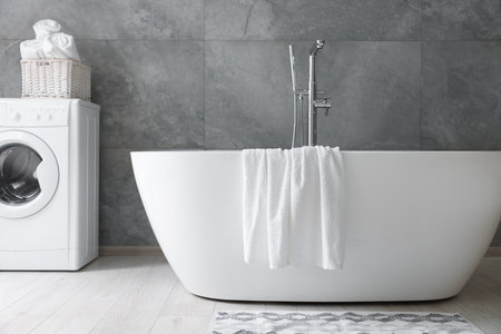 Fresh white towels on tub in bathroomの写真素材