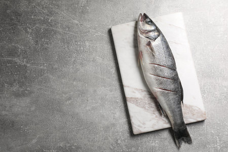 Fresh raw sea bass fish on light gray table, top view. Space for text