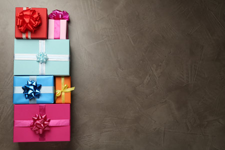 Many colorful gift boxes on gray table, flat lay. Space for text