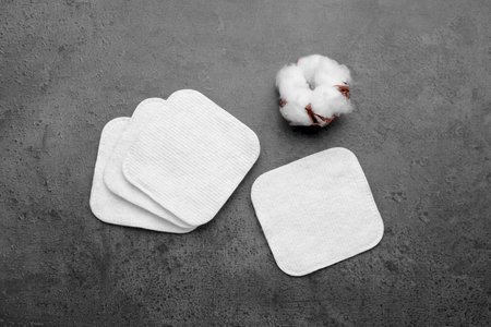 Many clean cotton pads and flower on gray background, flat lay