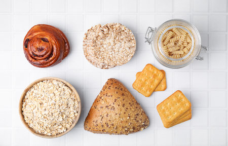 Different gluten free products on white tiled table, flat lay