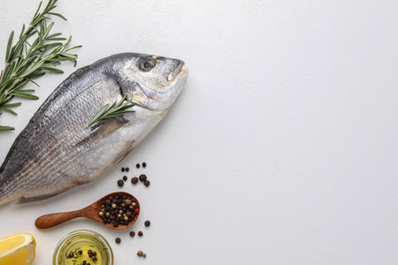 Flat lay composition with fresh raw dorado fish and ingredients on white table, space for textの写真素材