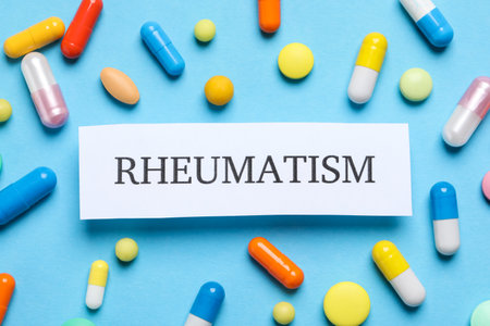 Card with word Rheumatism and pills on light blue background, flat lay
