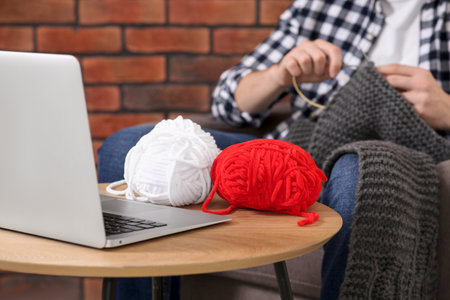 Man learning to knit with online course at home, closeup. Time for hobby