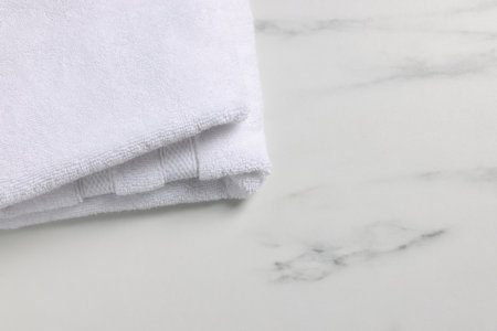 Clean folded towel on white marble table, space for textの写真素材
