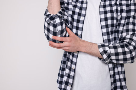 Man suffering from pain in his elbow on light background, closeup view space for text. arthritis symptomsの写真素材