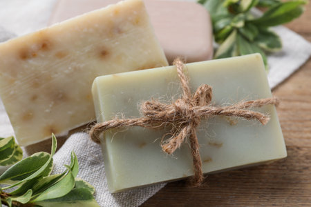 Soap bars and green plants on wooden table, closeupの写真素材