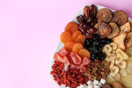 Plate with different dried fruits on violet background, top view. Space for textの写真素材