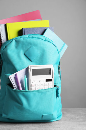 Turquoise backpack and different school stationery on table against gray backgroundの写真素材