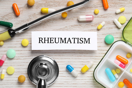 Card with word Rheumatism, stethoscope and pills on white wooden table, flat layの写真素材