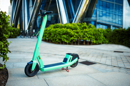 Green electric scooter on street near bushes outdoorsの写真素材