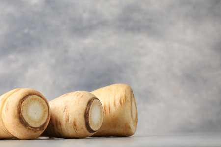 Many fresh ripe parsnips on gray table. Space for textの写真素材
