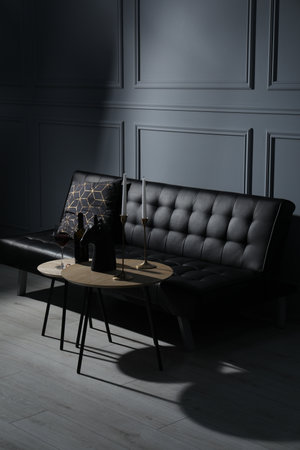 Elegant leather sofa and candlesticks on coffee table near light gray wall. interior designの写真素材