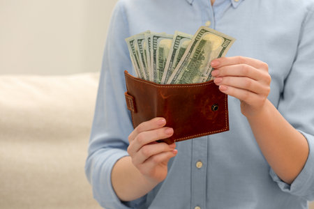Woman counting dollar bills indoors, closeup. money exchange