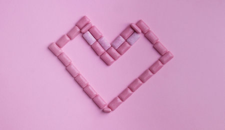 Heart made of sweet chewing gums on pink background, top viewの写真素材
