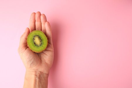 Woman holding delicious fresh kiwi on pink background, top view. Space for textの写真素材