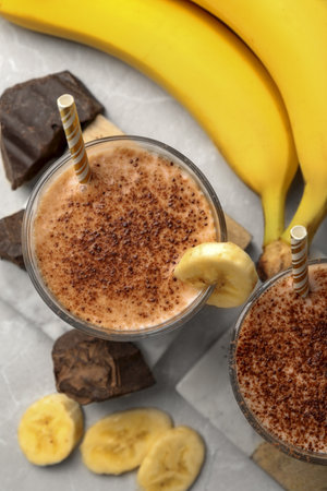 Tasty banana smoothie, fresh fruits and chocolate on white marble table, flat layの写真素材