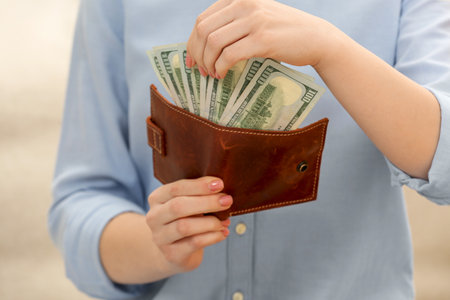 Woman counting dollar bills on beige background, closeup. money exchange