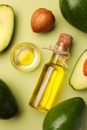 Cooking oil and fresh avocados on light green background, flat layの写真素材