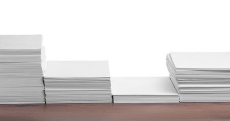 Stacks of paper sheets on wooden table against white backgroundの写真素材