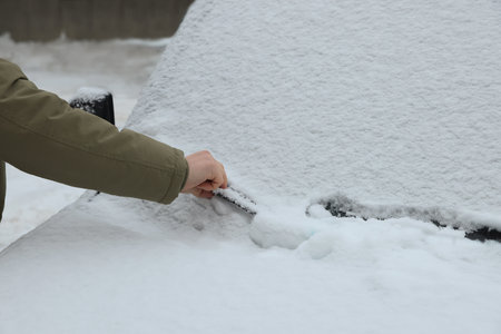 Woman cleaning car wiper blade covered with snow outdoors, closeupの写真素材