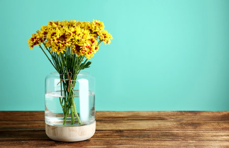 Vase with beautiful chrysanthemum flowers on wooden table. Space for textの写真素材