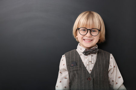 Happy little school child in uniform near chalkboard. Space for textの写真素材