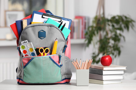 Backpack and different school stationery on white table indoorsの写真素材