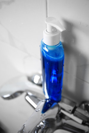 Bottle of shower gel on faucet in bathroom, above view