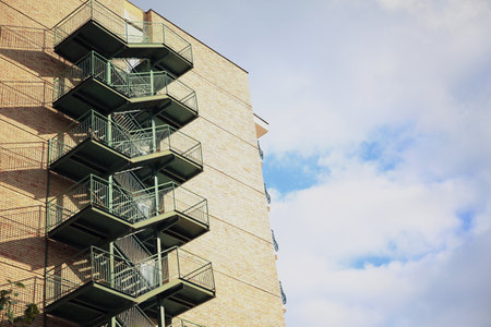 View of modern metal empty fire escape ladder near building on sunny day outdoors, space for textの写真素材
