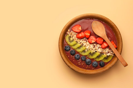 Bowl of delicious smoothie with fresh blueberries, strawberries, kiwi slices and oatmeal on color background, top view. Space for textの写真素材
