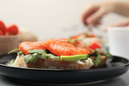 Tasty bruschetta with salmon, arugula and avocado on black plate, closeupの写真素材
