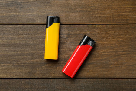 Yellow and red plastic cigarette lighters on wooden table, flat layの写真素材