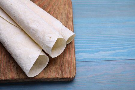 Delicious rolled Armenian lavash on light blue wooden table, space for textの写真素材