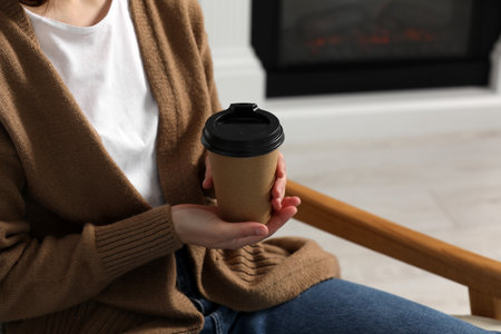 Woman holding takeaway cardboard cup indoors, closeup. Coffee to goの写真素材