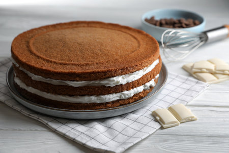 Delicious homemade layer cake and chocolate on white wooden table, closeup
