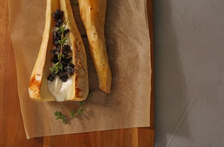 Tasty baked parsnips with sauce, prunes and thyme on light gray table, flat lay. Space for text