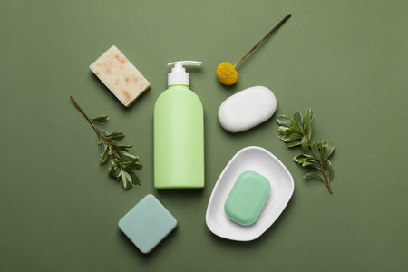 Soap bars and bottle dispenser on green background, flat layの写真素材