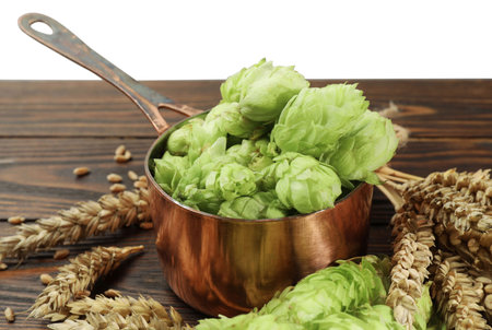 Fresh hop flowers and wheat ears on wooden table against white background, closeupの写真素材