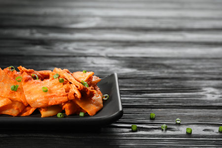 Delicious kimchi with Chinese cabbage and green onions on black wooden table, space for textの写真素材