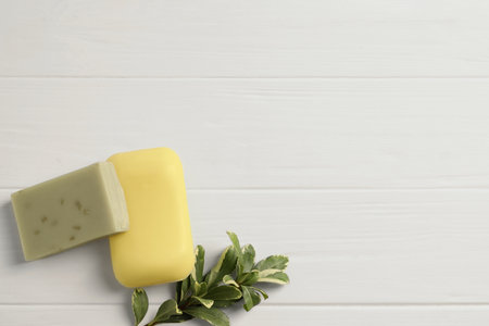 Soap bars and green plant on white wooden table, flat lay. Space for textの写真素材