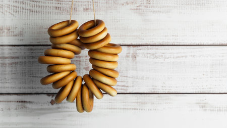 Bunch of delicious ring shaped Sushki (dry bagels) hanging near white wooden wall. Space for text