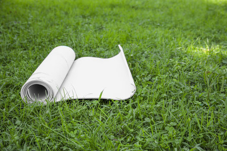 Karemat or fitness mat on green grass outdoors, space for textの写真素材